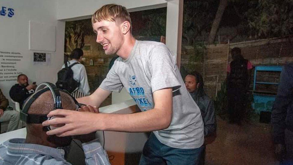 Ben Roberts putting a headset on a man in Senegal