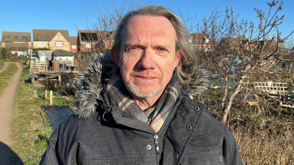 Jonathan Harris with long hair and beard in an allotment