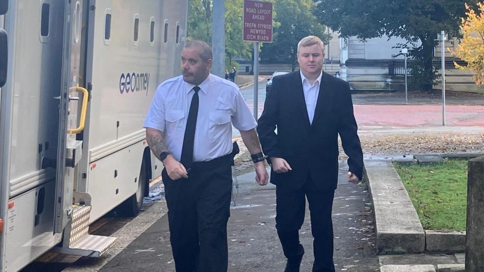 Darren brown being led by an officer into court