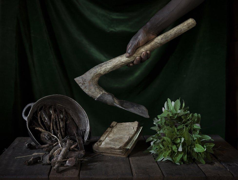 Objects on a wooden table and a hand holding a farming tool