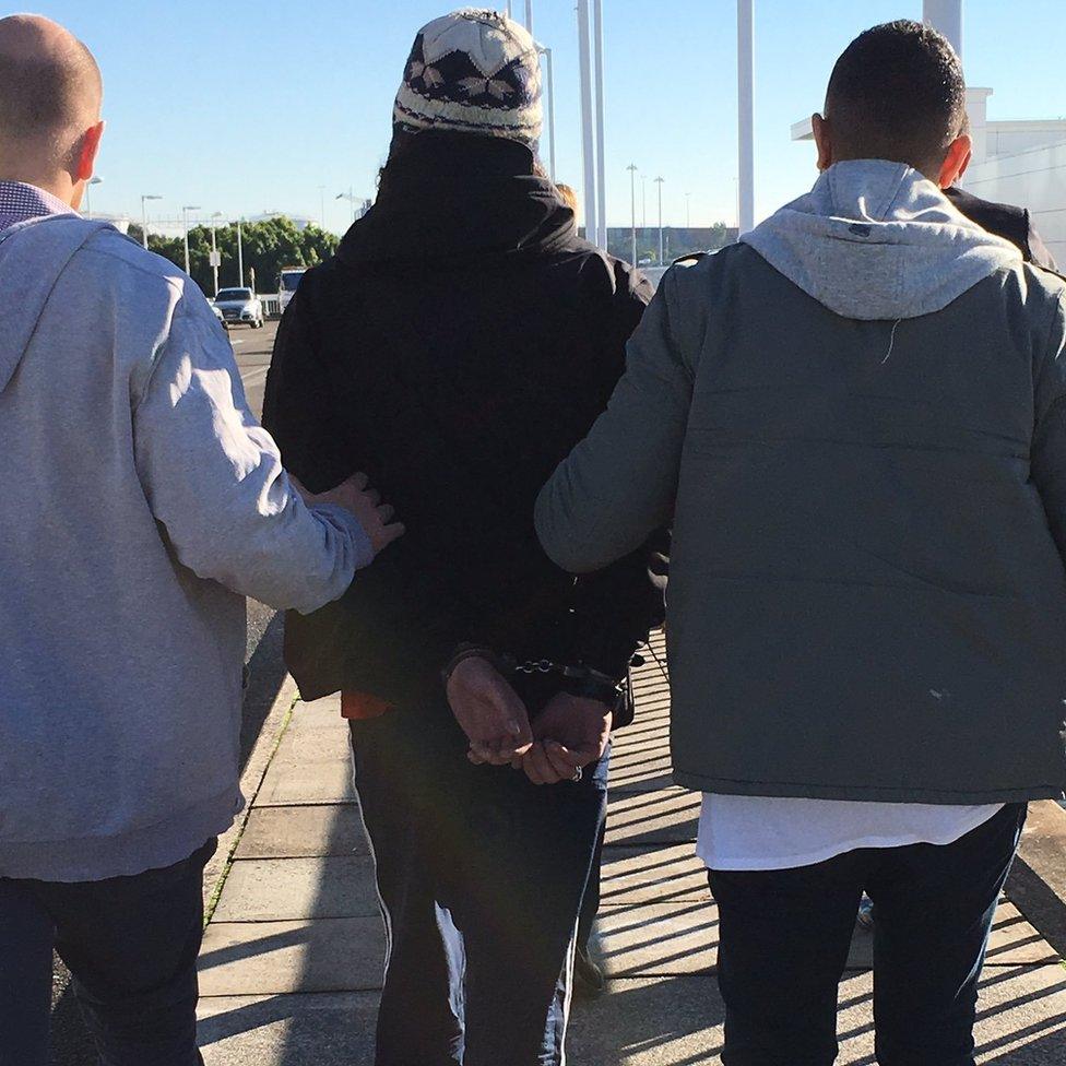 A photo posted on Twitter shows two plainclothes officers outside the terminal leading the man in handcuffs.