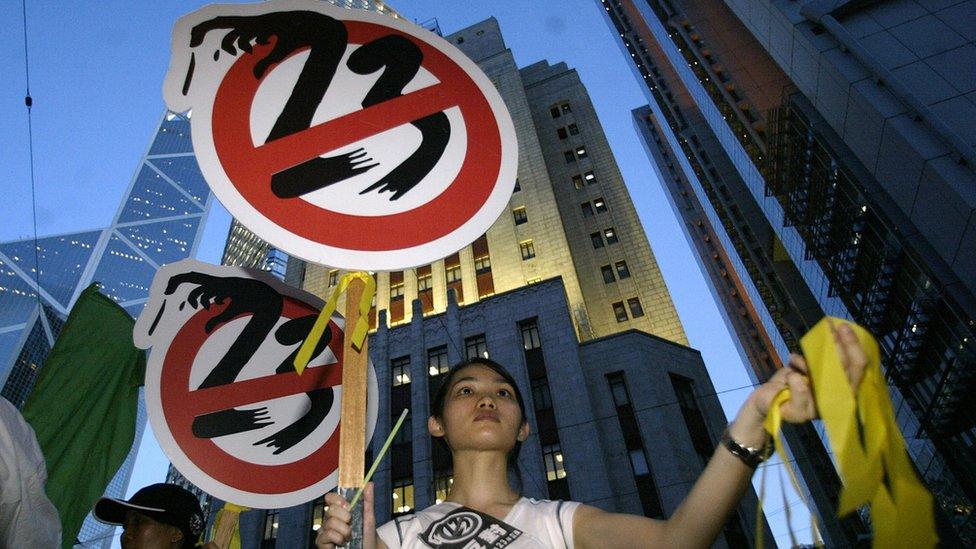 A girl hands out yellow ribbons against the controversial Article 23 law during a protest