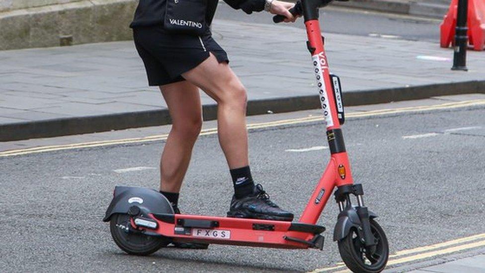 A man riding a Voi scooter