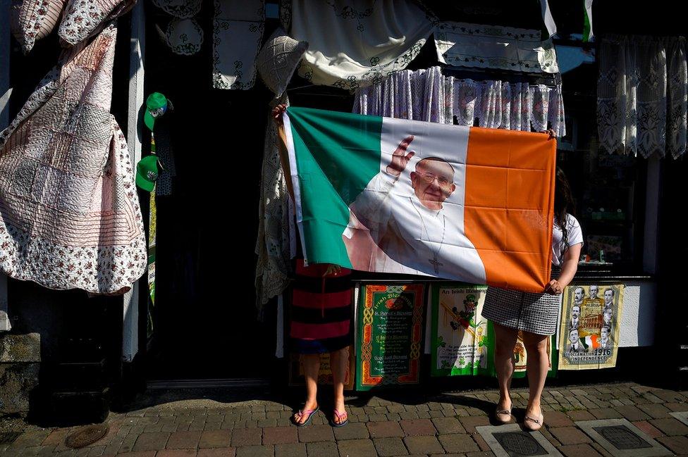 Women from a haberdashery shop hold up their new Pope Francis Ireland flag