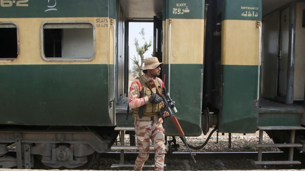 A Pakistan Army soldier stands guard next to a rescue train