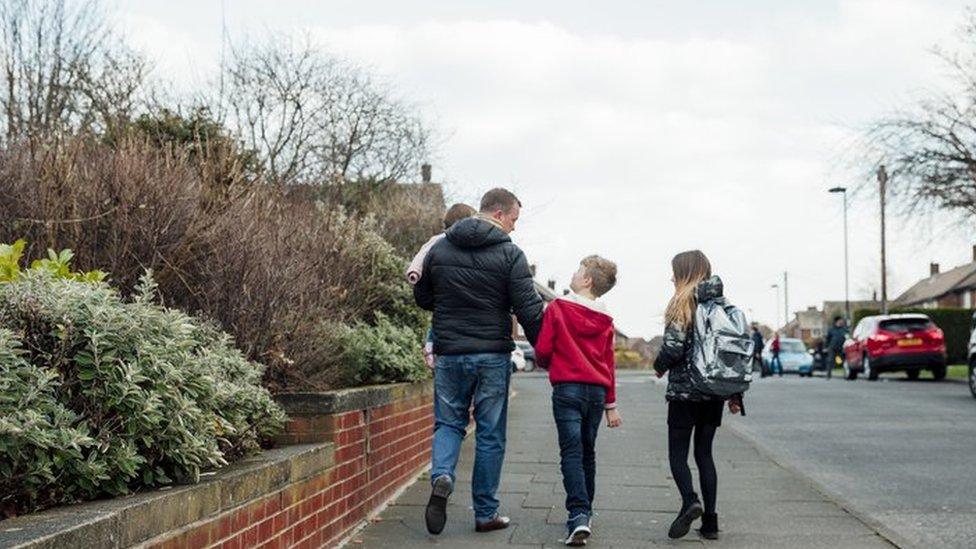 Stock image of a father walking with his children