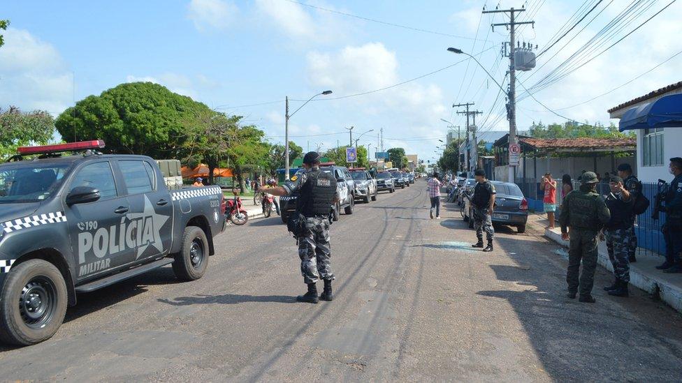 Police officers stand guard outside a police station attacked during a bank robbery