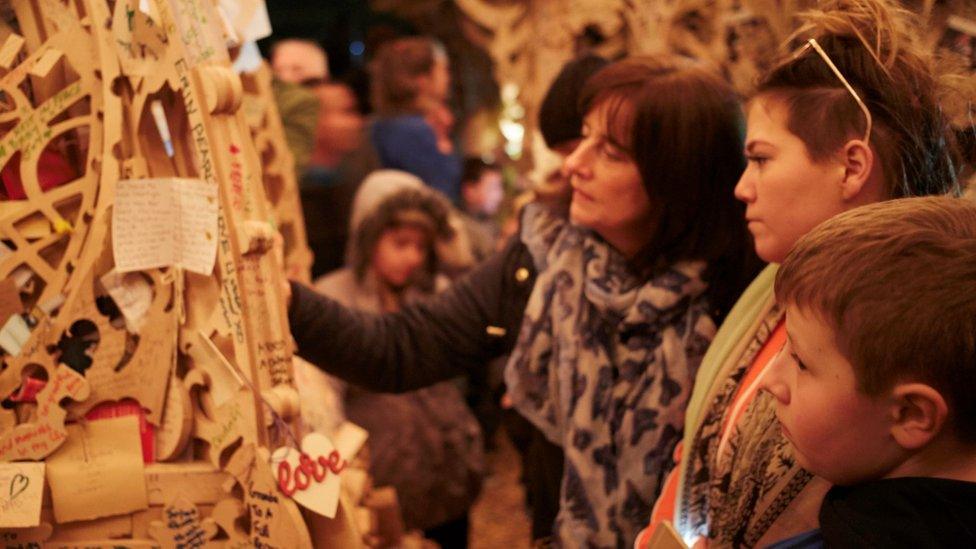 People looking at wooden structure