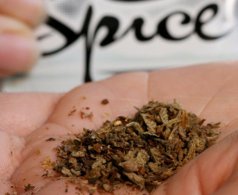 A young woman holds up a bag of "Spice"