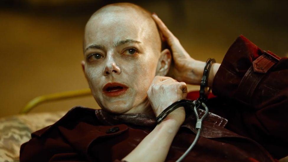 Emma Stone as seen in Bugonia, with a shaved head and in handcuffs