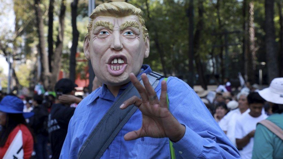 A man wears a mask depicting US President Donald Trump during a march demanding respect for Mexico and its migrants, 12 February 2017