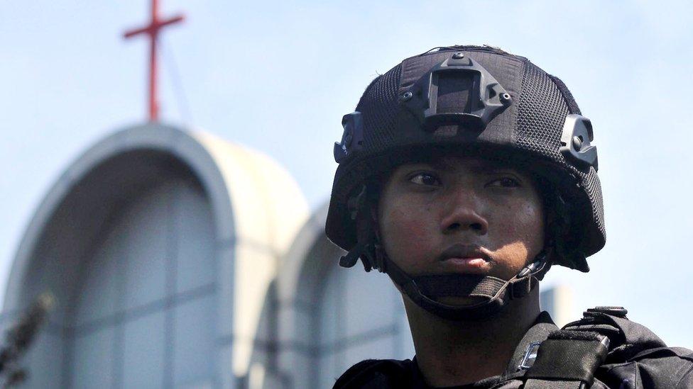 An Indonesian police officer stands guard near the scene of a bomb blast in front of a church in Surabaya, Indonesia, 13 May 2018