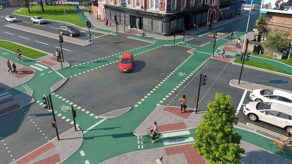 An artist's impression of the completed route at a junction. There are cars waiting at the traffic lights, and there is a green cycle path coming from every direction.
