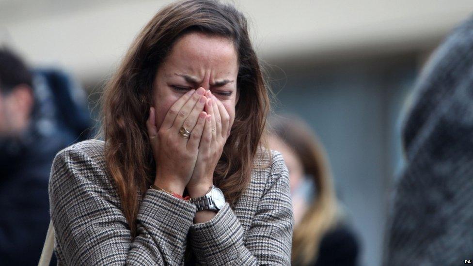 A woman shows emotion outside Le Carillon bar in Paris