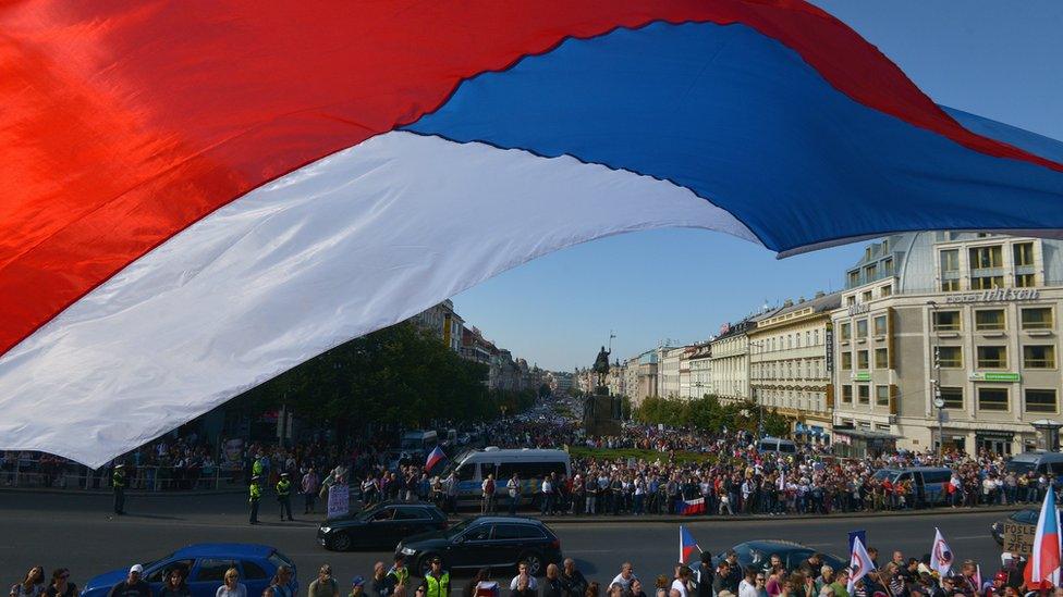 A Czech national flag flies over protesters attending an anti-migrants demonstration on September 12, 2015 in Prague.