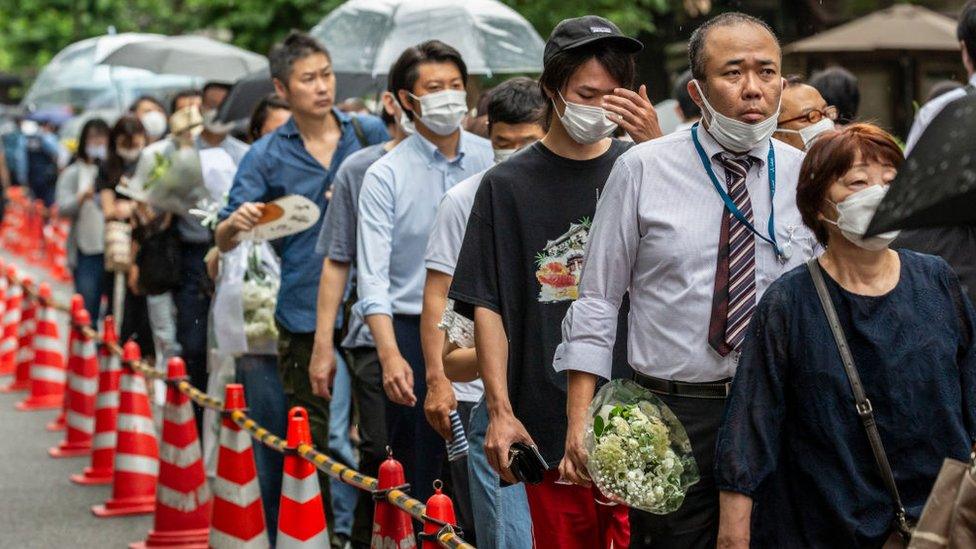 People wait in line to attend the funeral for former Japanese Prime Minister Shinzo Abe at Zojoji temple on July 12, 2022 in Tokyo, Japan.