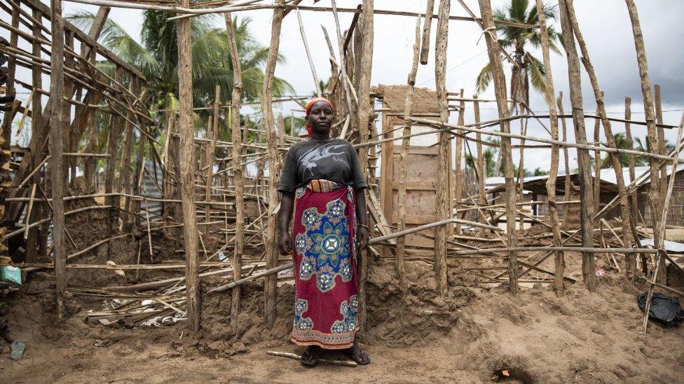 A lady who fled violence in northern Mozambique stands in front of her temporary house destroyed by Cyclone Kenneth