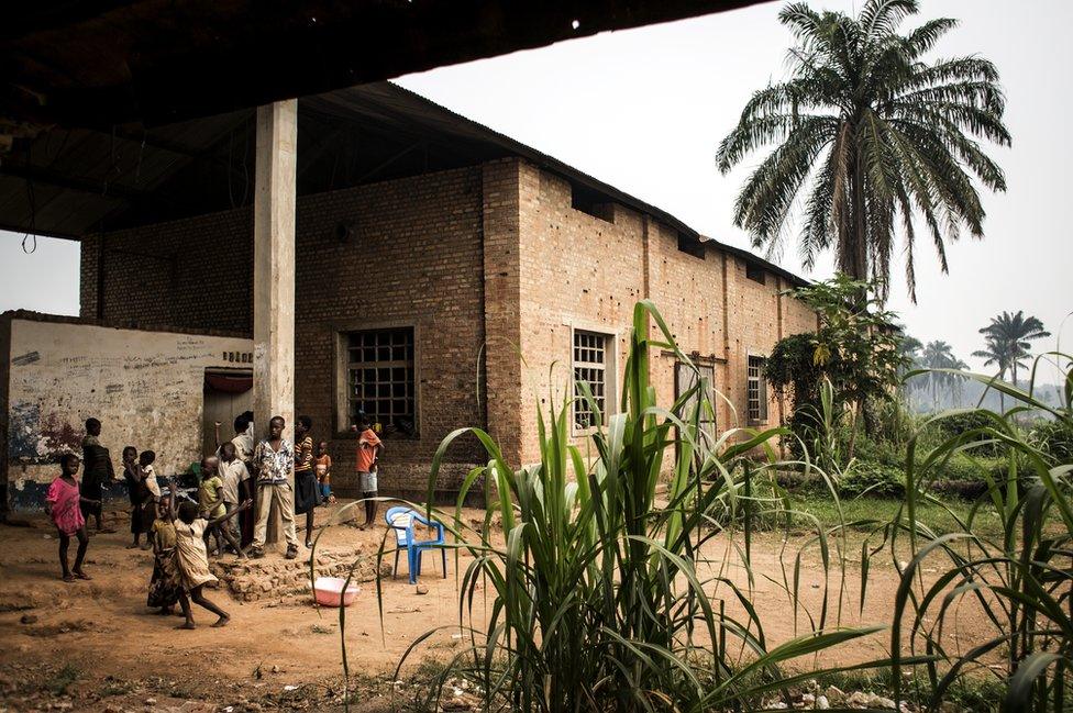 Displaced persons outside an abandoned warehouse, which is used by Internally Displaced Persons (IDPs) as a shelter from the ongoing conflict