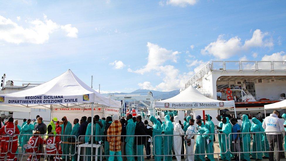 Migrants stand as they disembark from "Nave Diciotti" Italian Coast Guard vessel in the Sicilian harbour of Messina, Italy, November 24, 2017