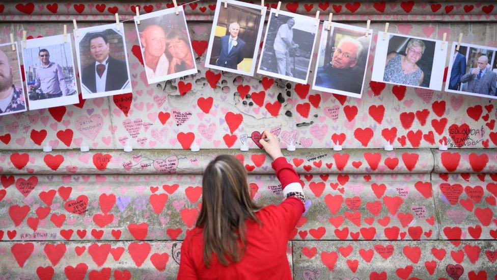 Woman writes on Covid memorial wall in London