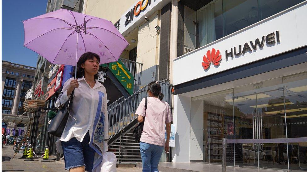 People walk past a Huawei store on July 1, 2019 in Dongdaqiao, Chaoyang District, Beijing.