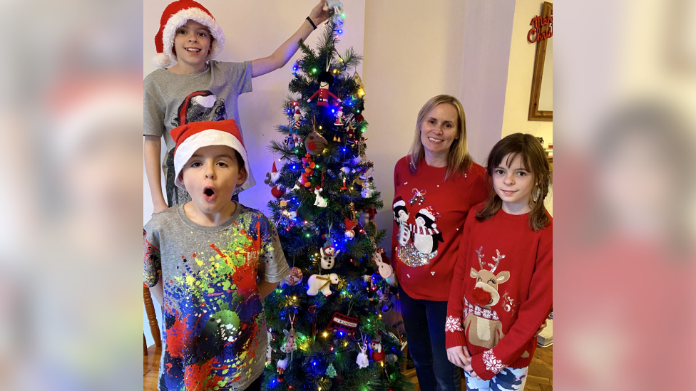 children and mother around Christmas tree