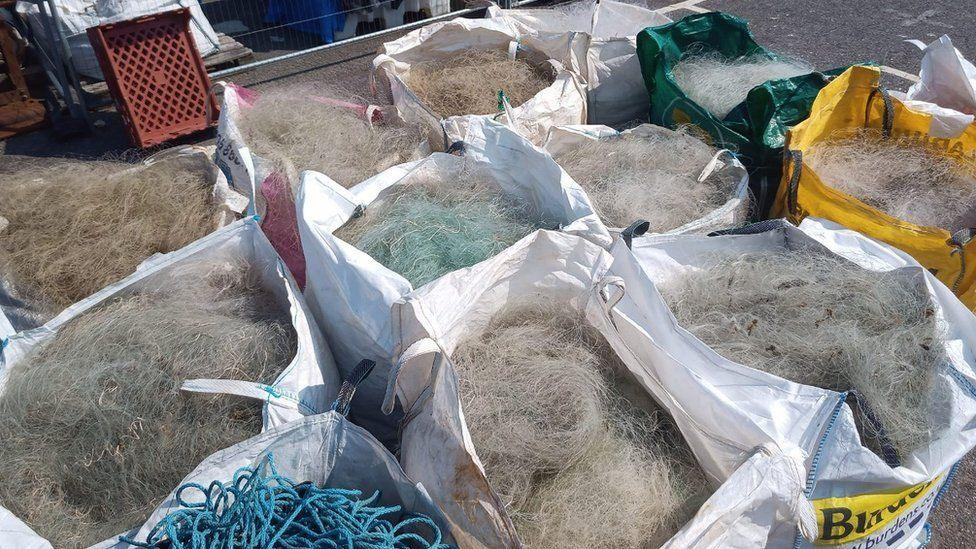 Bulk bags lined up, filled with fine fishing nets and blue rope 