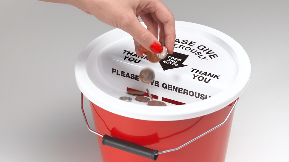 Charity box with money being put in