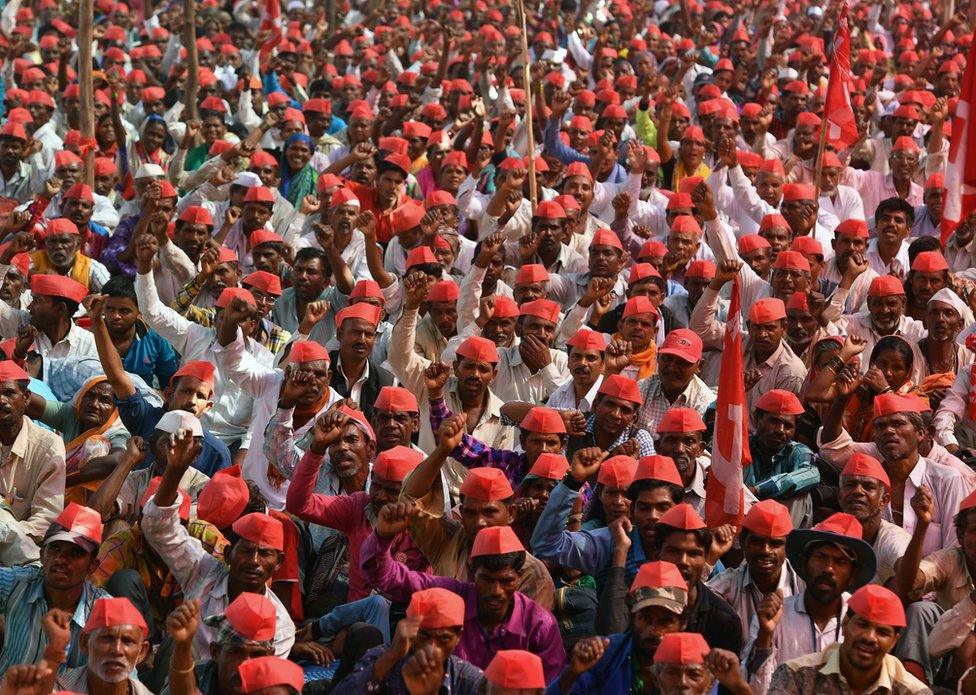 Farmers shout slogans as they listen to speakers during a protest