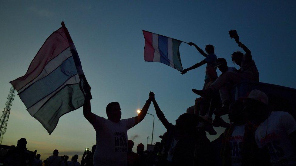 People celebrate in the streets with Gambian flags as they hear of the imminent departure of former Gambian leader Yahya Jammeh in Banjul on January 21, 2017