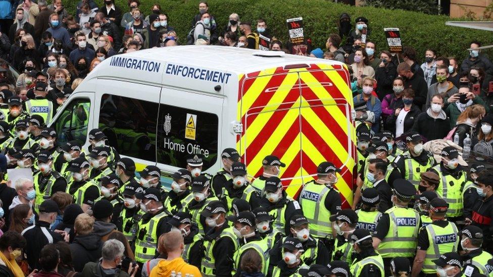 People surrounding immigration van