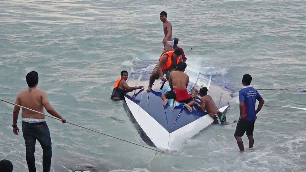 Rescuers on top of the capsized boat