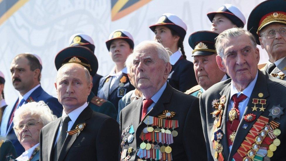 Vladimir Putin and veterans watch a military parade in Moscow on 24 June