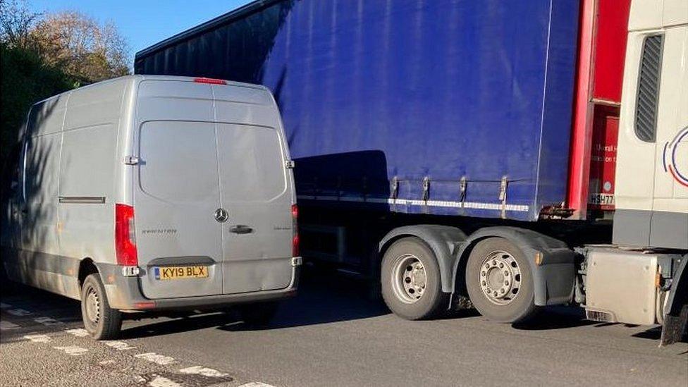 Large blue lorry meets grey van coming in the opposite direction on a bend on the A422