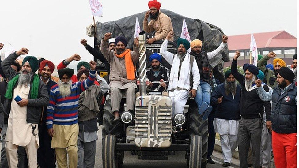 Farmers shout slogans as they make their way along the road to Delhi