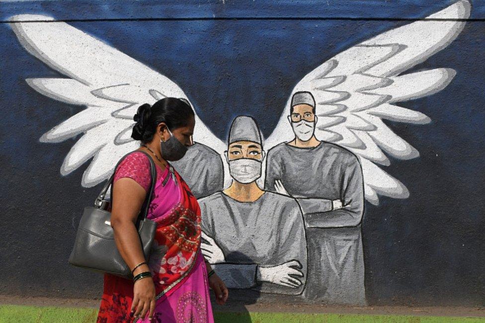 A woman wearing a face mask walks past a graffiti painted to create awareness about the coronavirus disease. Graffiti, besides creating awareness about coronavirus pandemic, it is painted to beautify the walls in Vashi (a suburb in Navi Mumbai).