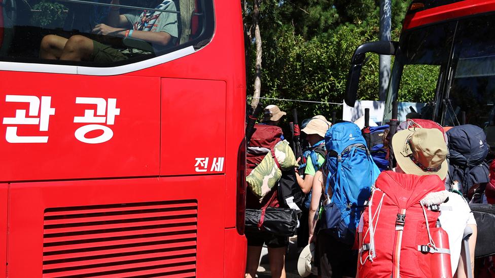 Participants sitting inside a bus give a thumbs-up as they prepare to leave the camping site of the 25th World Scout Jamboree in Buan, South Korea, on 8 August 2023