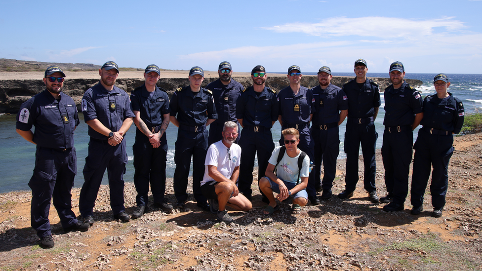 a group of about a dozen Royal Navy sailors posing for a photo