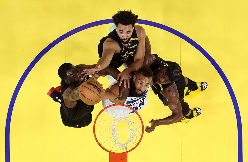 Draymond Green, Trayce Jackson-Davis, and Jimmy Butler of the Golden State Warriors surround Minnesota's Rudy Gobert at the rim in competing for a rebound. Photo by Ezra Shaw