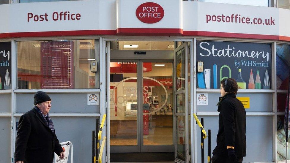 People walking past a Post Office branch