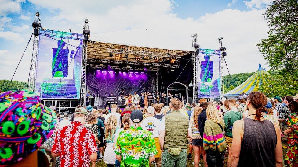 People wearing brightly coloured clothes gathered around an outdoor stage