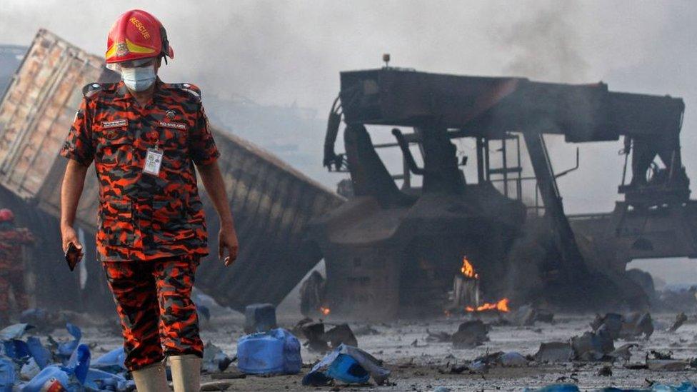 A rescuer walks through the debris of the fire