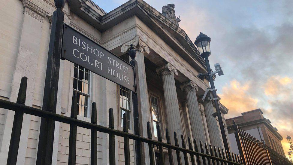 The courthouse in Londonderry with the entrance and sign seen through railings