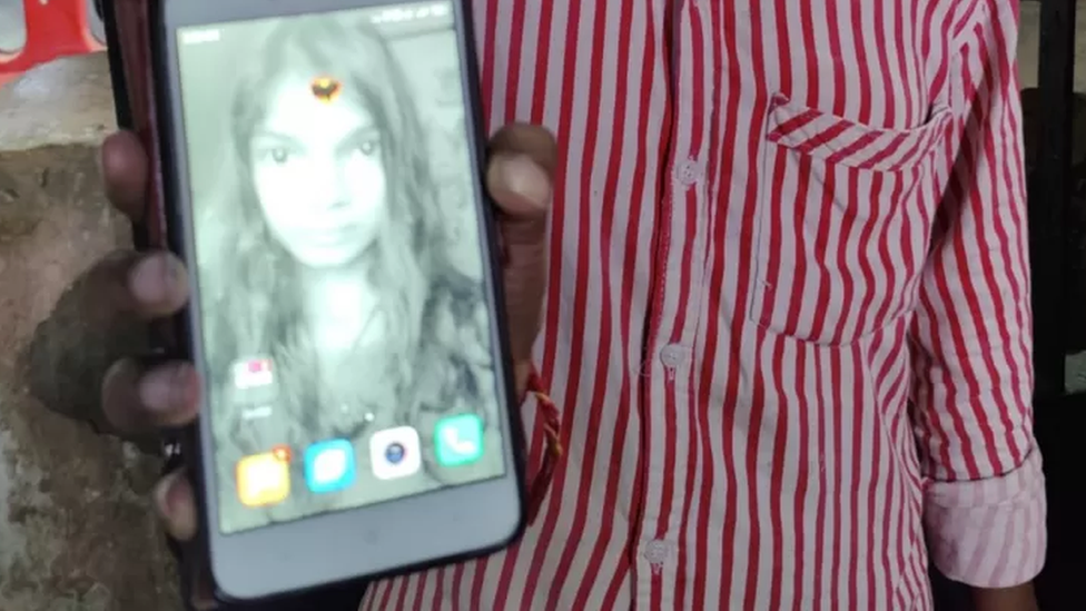 An Indian teenager holds up a photo of her missing sister