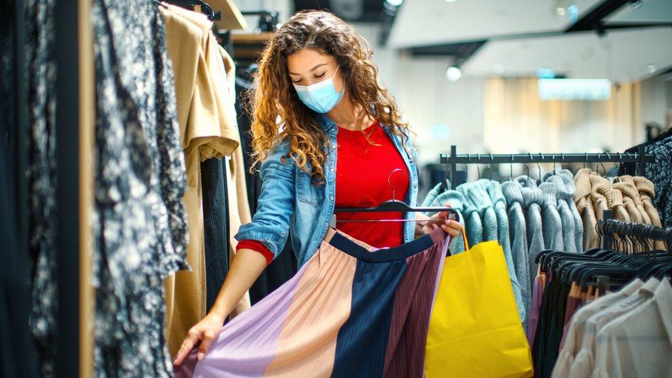 A woman wearing a mask shopping for clothing