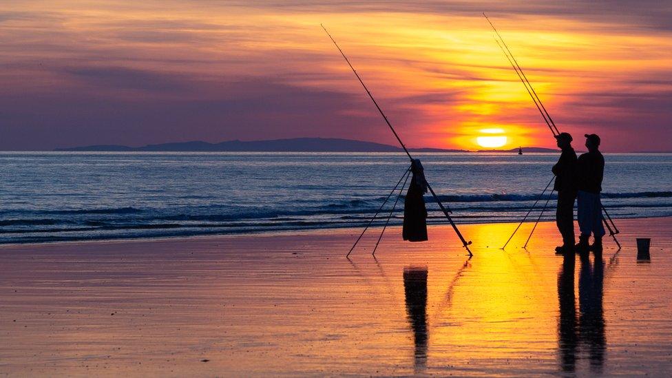 Fishermen on the beach at Tywyn, Gwynedd, with Llyn Peninsula in the distance