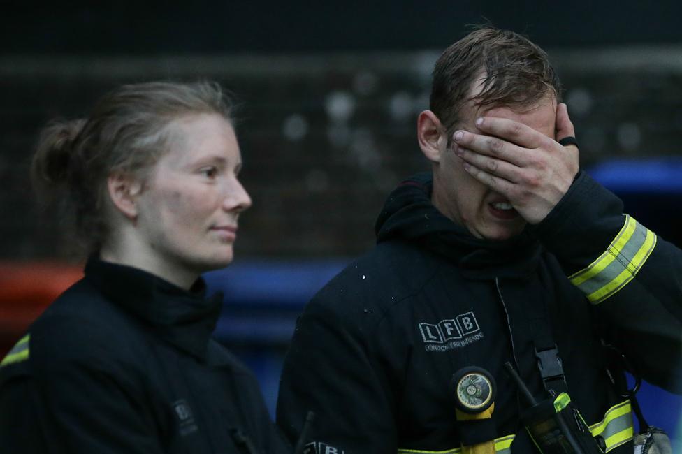 Firefighters wait outside Grenfell Tower