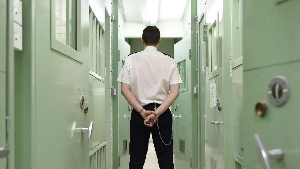 Rear view of a prison officer in a prison corridor