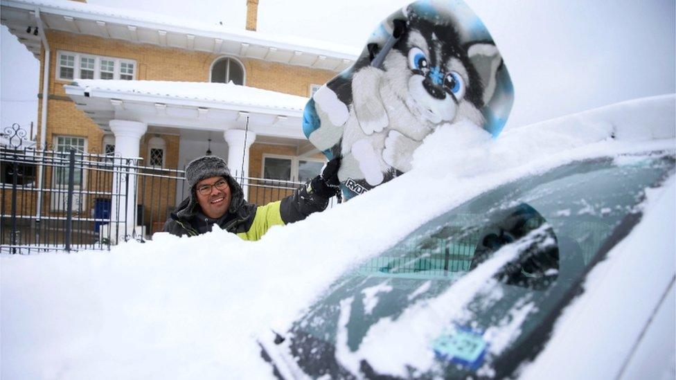 Francisco Sanchez wipes snow off his car with a boogie board before going out sledding with his kids on Valentine's Day at Memorial Park in El Paso, Texas, US, 14 February 2021