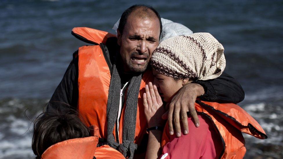 A family reacts after arriving, with other refugees and migrants, on the Greek island of Lesbos (October 28, 2015)